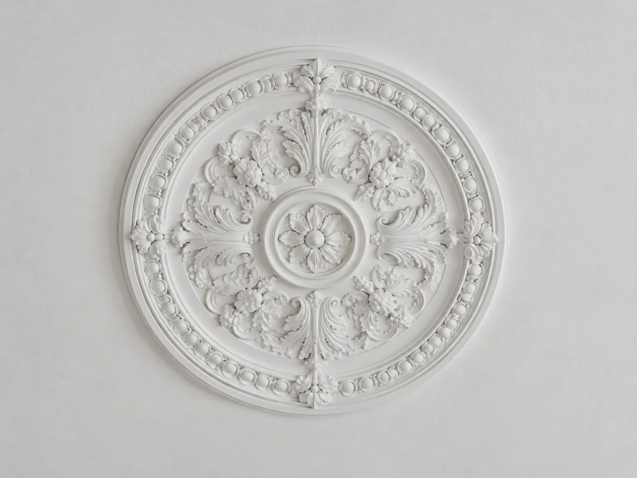 Weiße Stuckrosette mit Blütenornament an einer Decke
